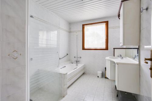La salle de bains blanche est pourvue d'une baignoire, de 2 lavabos et d'une douche. dans l'établissement Maison pour 8 avec jardin avec vue sur le port, à Pléneuf-Val-André