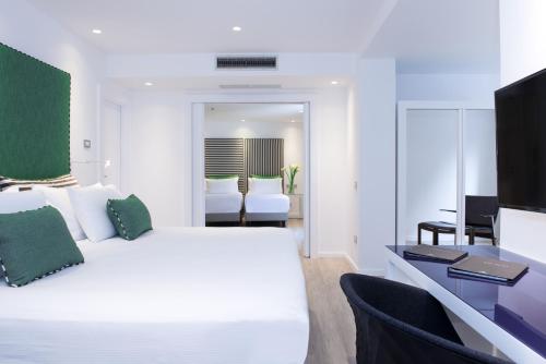 a white bedroom with a white bed and a desk at Hilton Sorrento Palace in Sorrento