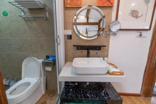 a bathroom with a sink and a toilet and a mirror at Lijiang Old Town Meiliju View Inn in Lijiang