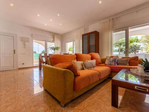 a living room with an orange couch and a table at Holiday Home Dani by Interhome in L'Eucaliptus