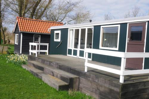 a blue and white tiny house on a wooden deck at Hoeve Zorglust, salonwagen voor 2 personen met extra slaapkamerhuisje voor 2 - 3 kinderen in Koudekerke
