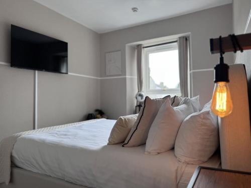 a bedroom with a bed with white sheets and pillows at The Glendevon Hotel in Auchterarder