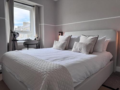 a white bed with white pillows and a window at The Glendevon Hotel in Auchterarder