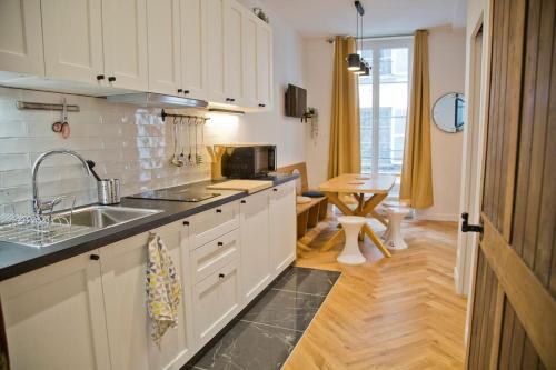 une cuisine avec des armoires blanches et un évier dans l'établissement Fully Renovated Historic Apt in Heart Mouffetard, à Paris
