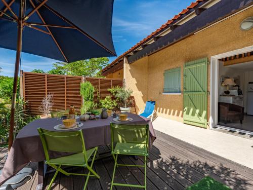 une table avec des chaises vertes et un parasol sur une terrasse dans l'établissement Holiday Home Les Brigantines 1 et 2-6 by Interhome, à Saint-Cyprien