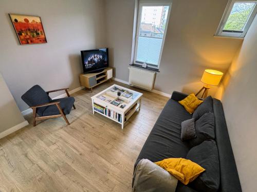 a living room with a couch and a tv at Le Boisseliège in Liège