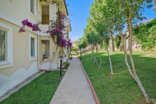 a walkway in front of a building with purple flowers at Larimar Suite Hotel in Oludeniz