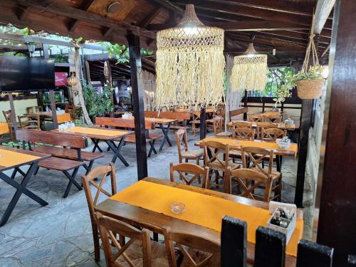 a restaurant with wooden tables and chairs and chandeliers at Guest House Starata Kushta in Lozenets