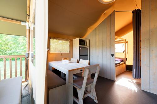 a tiny house with a table and chairs on a balcony at Glamping de Schatberg in Sevenum