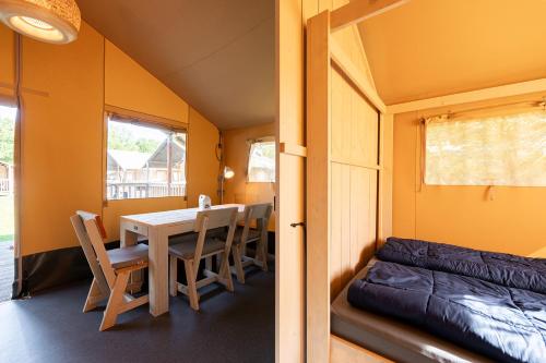 a dining room with a table and chairs and a couch at Glamping de Schatberg in Sevenum