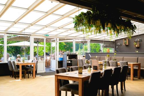 a restaurant with tables and chairs and windows at Glamping de Schatberg in Sevenum