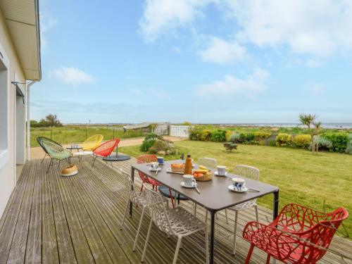un patio avec une table et des chaises sur une terrasse dans l'établissement Holiday Home Les pieds dans l'eau by Interhome, à Penmarcʼh