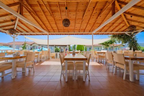 a dining room with tables and chairs and a wooden ceiling at Larimar Suite Hotel in Oludeniz