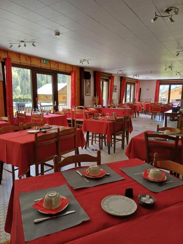 une salle à manger avec des tables rouges, des chaises et des fenêtres dans l'établissement Hotel et centre de vacances Le Choucas, à Sixt-Fer-à-Cheval