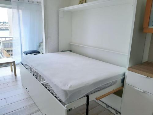 - un lit blanc dans une chambre avec un miroir dans l'établissement Studio rénové port Gruissan, à Gruissan