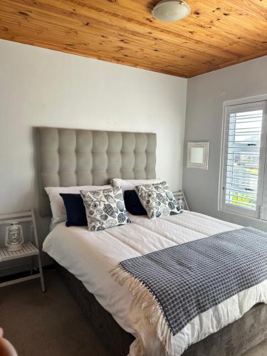 a bedroom with a large bed with a wooden ceiling at Huisie by die See in Gansbaai