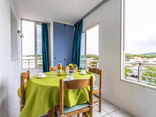 une salle à manger avec une table verte et des fenêtres dans l'établissement Apartment La Palme d'Or-20 by Interhome, au Cap d'Agde