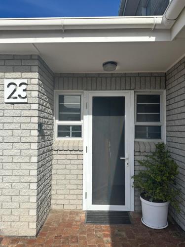 a house with a white door and a potted plant at Huisie by die See in Gansbaai