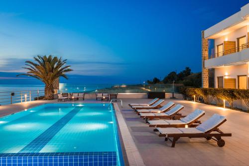 a swimming pool with lounge chairs next to a building at Niki Beach Hotel in Kamariotissa