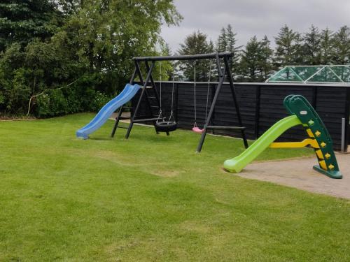 a playground with two swings in the grass at Landstedet Billund in Billund