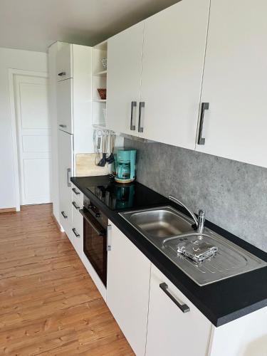 a kitchen with white cabinets and a sink at Ferienwohnung Nr 4 in Hinrichsdorf