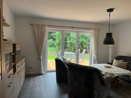 a living room with a table and chairs and a sliding glass door at Haus Kanalliebe in Nübbel