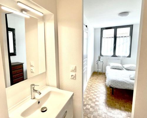 a bathroom with a sink and a mirror and a bed at 2 chambres doubles, centre-ville historique in Chinon