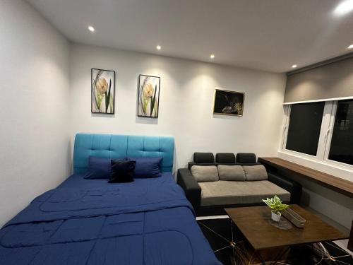 a bedroom with a blue bed and a couch at AR Homestay Riverine 2 King in Kuching