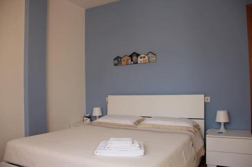 a bedroom with a white bed with blue walls at Appartamento Le Palmine in Cento