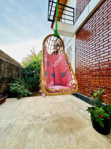 a pink swing hanging from a brick wall at Neems paradise in Point Pedro