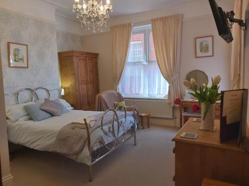 a bedroom with a bed and a dresser and a desk at Boulmer Guest House in Whitby