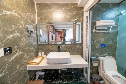 a bathroom with a sink and a mirror and a toilet at Lijiang Old Town Meiliju View Inn in Lijiang