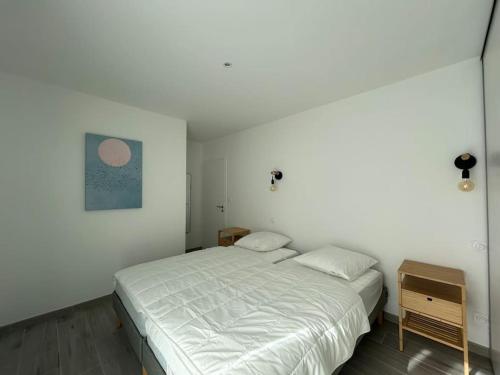 a white bedroom with a bed and a night stand at La Forêt d'Armotte villa 19 in Saint-Augustin