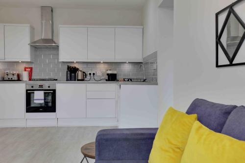 a kitchen with white cabinets and a blue couch at Chelmer Springs Maisonettes in Chelmsford