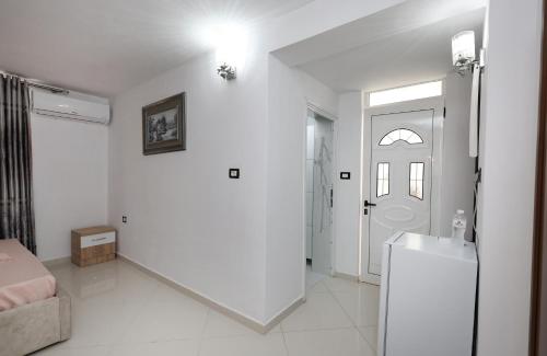 Una sala de estar blanca con un refrigerador y una puerta. en Guesthouse Berati, en Berat