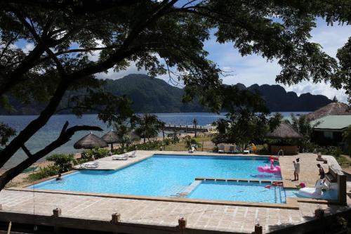a large swimming pool next to a body of water at Baia Serena Resort in Coron