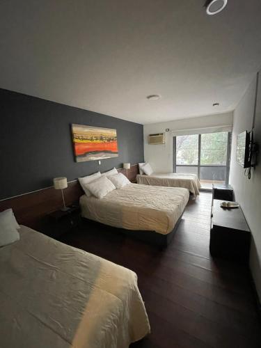 a hotel room with two beds and a window at Costalago Suites Hotel in Villa Carlos Paz
