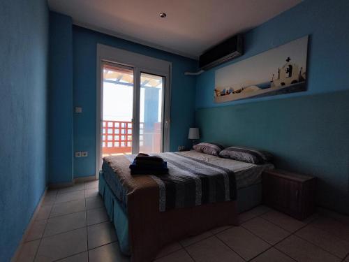 a blue bedroom with a bed and a window at Sozopoli Seaview in Sozopoli