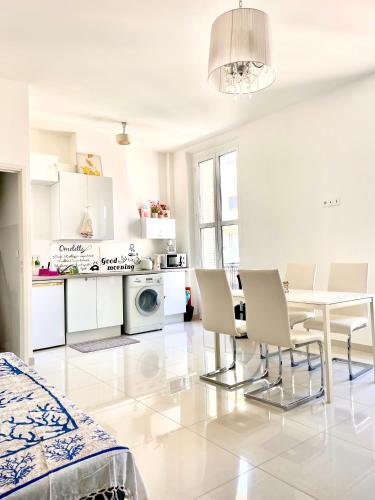 un salon blanc avec une table et des chaises dans l'établissement Cannes plage 2 pièces Croisette centre ville, à Cannes
