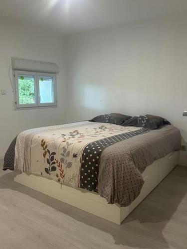 un lit dans une chambre blanche avec une fenêtre dans l'établissement Maison à la campagne vu sur Pyrénées avec jardin, à Montégut-Bourjac