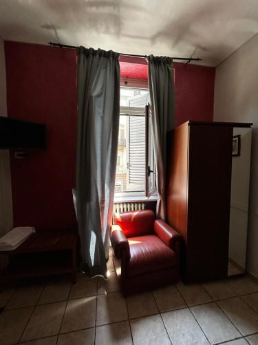 a living room with a red chair and a window at Hotel Ferrucci in Turin