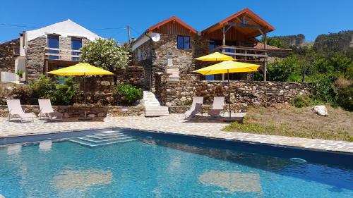 a swimming pool with chairs and umbrellas in front of a house at Villa Leonardo in Vale de Cameiro