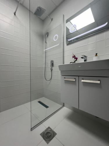 a white bathroom with a shower and a sink at Comfort Deluxe Kosmos Apartments in Ohrid