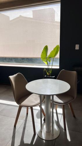 a white table with two chairs and a potted plant at Costalago Suites Hotel in Villa Carlos Paz