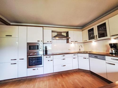 a large white kitchen with white cabinets and appliances at Apartment Kröll beim Geislerhof by Interhome in Ramsau
