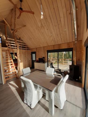 une salle à manger avec une table et des chaises blanches dans l'établissement Ecolodge des Monts d'Arrée & spa, à La Feuillée