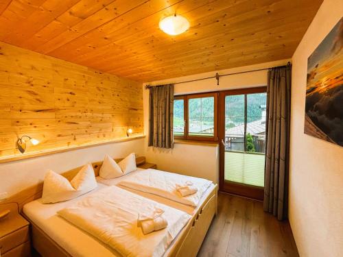 a bedroom with a bed and a large window at Appartementhaus Sonnleitn in Kals am Großglockner
