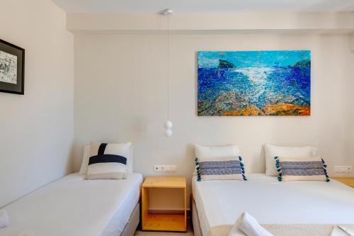 two beds in a room with a painting on the wall at Hotel Kamelo in Vari