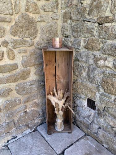 a wooden stand with a vase on a stone wall at Mas Loisonville - Demeure d'exception & Spa en Drôme Provençale in Grillon