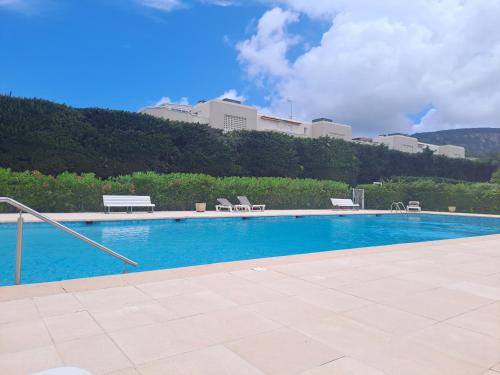 une piscine avec des chaises et un bâtiment en arrière-plan dans l'établissement Belle situation au calme, à Mandelieu-la-Napoule